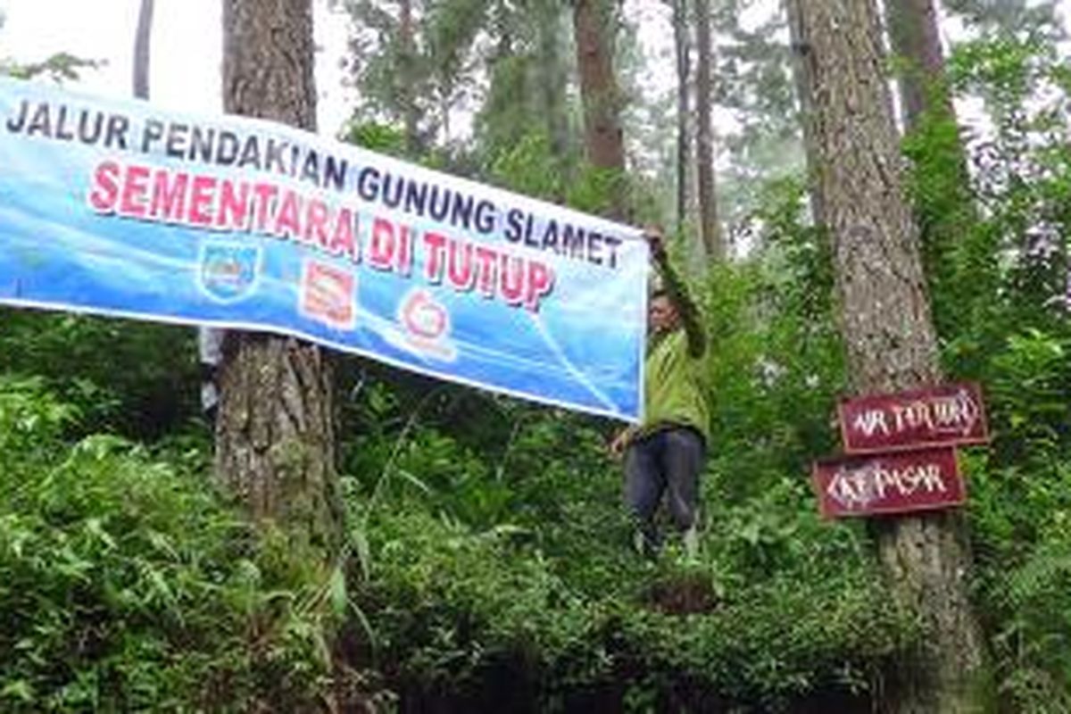 Salah seorang anggota Gabungan Pencinta Alam Gunung Slamet memasang banner himbauan untuk para pendaki nekad di sejulah titik di jalur pendakian di Desa Guci ,Bumijawa, Tegal, Rabu (12/3/2014). 