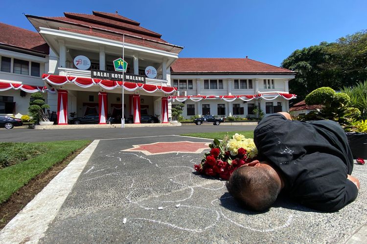 Seniman bernama Mukmin Ahmad (44) dari Malang Performance Art Community melakukan aksi teatrikal dengan menggambar jejak tubuhnya sendiri di halaman Balaikota Malang pada Kamis (10/8/2023), siang.