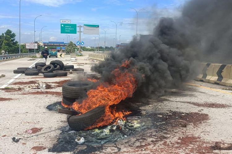 Ban mobil bekas yang dibakar oleh ahli waris saat menggelar aksi protes terkait uang ganti rugi lahan atau dana konsiyansi terkait pembangunan jalan tol Cimanggis - Cibitung di GT Jatikarya, Rabu (8/2/2023).