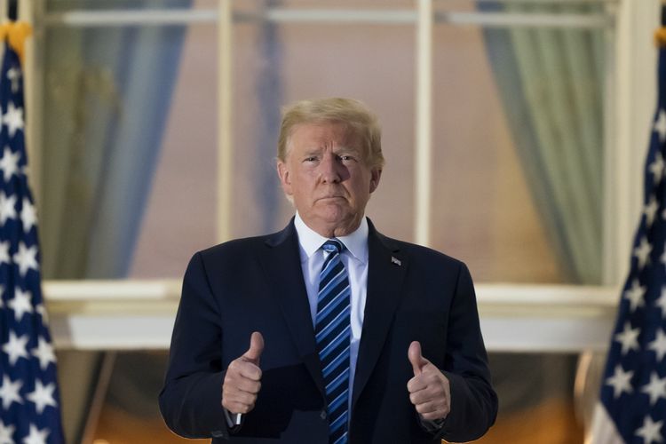 Presiden Amerika Serikat Donald Trump mengacungkan dua jempol saat berdiri di balkon Blue Room usai kembali ke Gedung Putih pada Senin (10/5/2020) dari rumah sakit militer. Walter Reed tempat dia dirawat karena Covid-19.