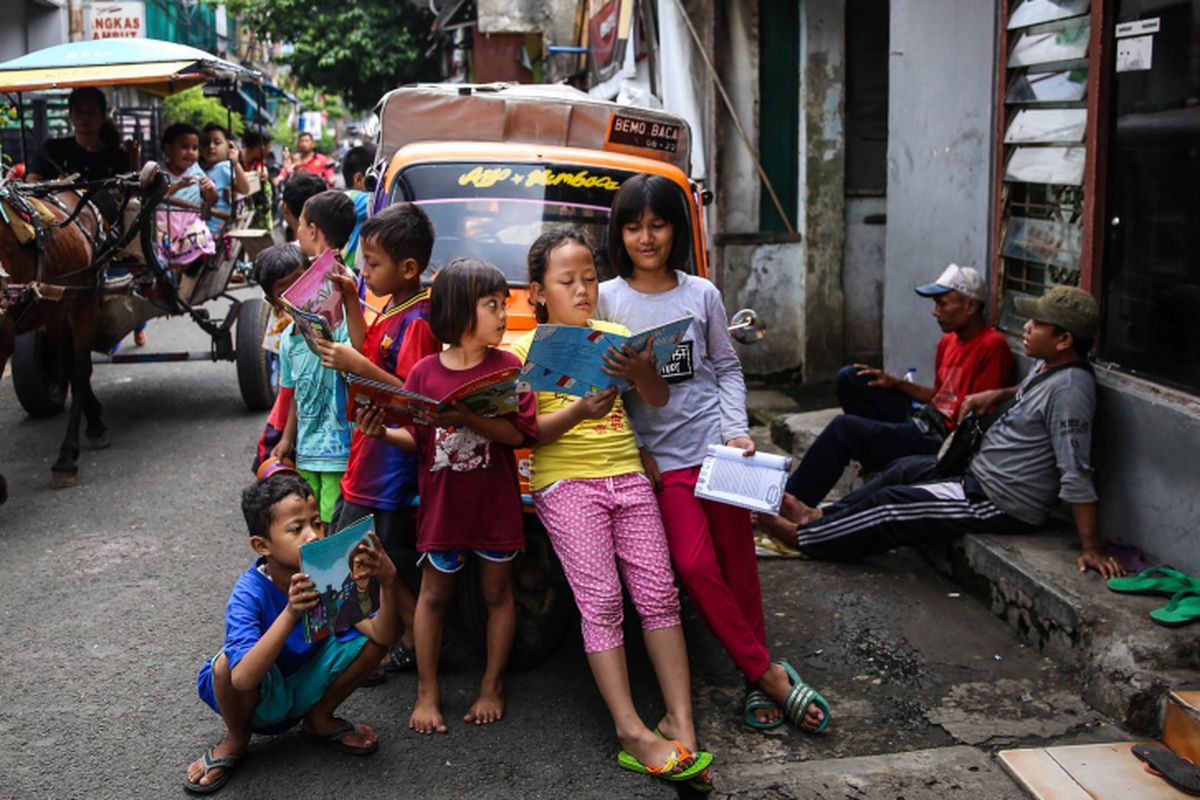 Anak-anak membaca buku di bemo perpustakaan di Jalan Karet Pasar Baru Barat II, Tanah Abang, Jalarta Pusat, Jumat (7/12/2018). Pak Sutino (58) adalah sopir bemo yang merintis bemo tuanya menjadi perpustakaan keliling bagi anak-anak sejak tahun 2013.  Pak Sutino (58) adalah sopir bemo yang merintis bemo tuanya menjadi perpustakaan keliling bagi anak-anak sejak tahun 2013.