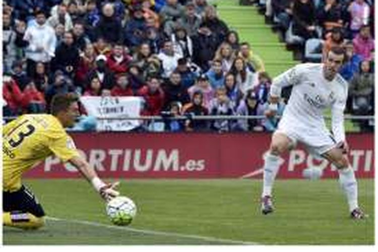 Penyerang Real Madrid Gareth Bale (kanan) melepaskan tembakan yang berusaha dihalau kiper Getafe, Vicente Guaita, dalam lanjutan La Liga di Coliseum Alfonso Perez, Getafe, Minggu (16/4/2016). Bale mencetak satu gol ini untuk membawa Real Madrid menang 5-1.