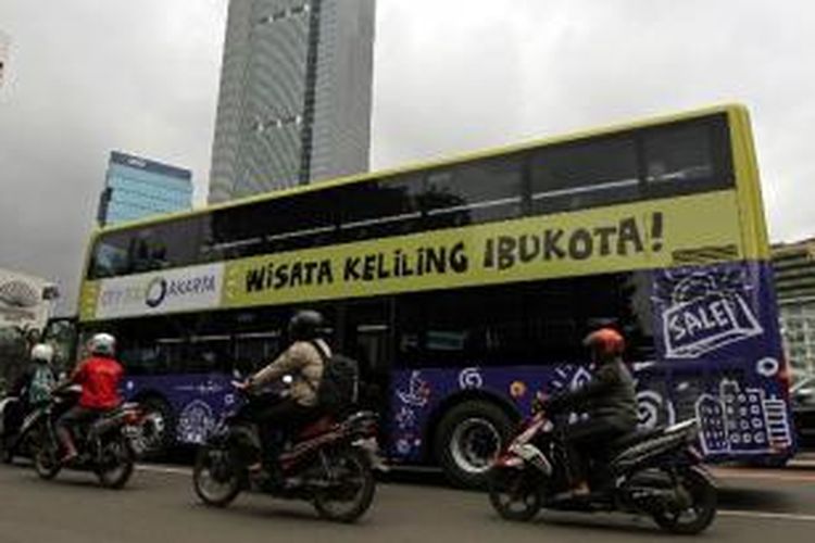 Bus tingkat wisata melintas di sekitar Bundaran HI, Jakarta Pusat, untuk diperkenalkan kepada masyarakat, Kamis (16/1/2014). Pemprov DKI Jakarta mendatangkan lima bus tingkat dari China untuk meningkatkan pariwisata, yang akan mulai dioperasikan awal Februari.