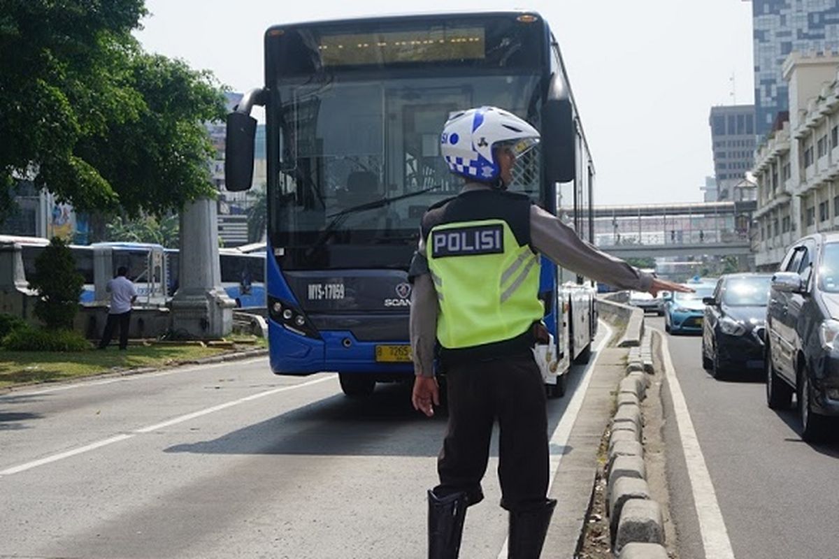 Seorang polisi tengah berdiri di depan bus Transjakarta, Senin (12/6/2017) siang.