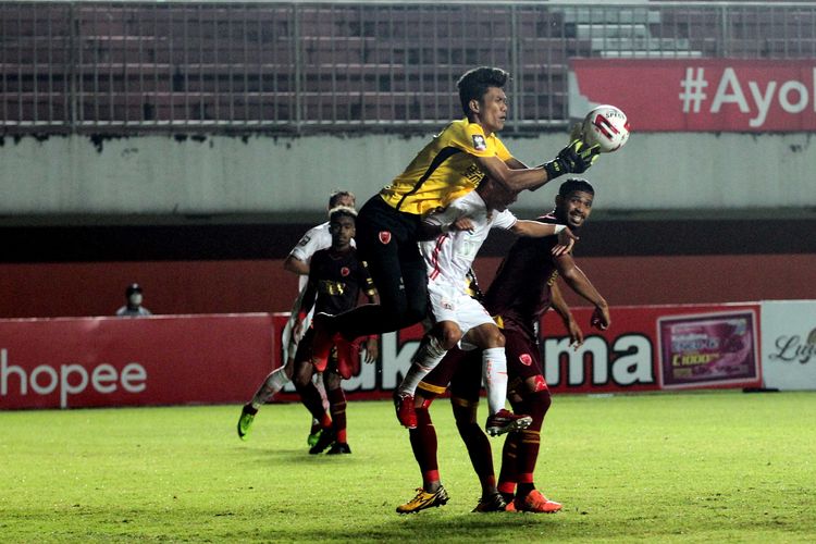 Penjaga gawang PSM Makassar Hilman Syah menangkap bola sundulan pemain Persija Jakarta Riko Simanjuntak (tengah) saat babak semifinal Piala Menpora 2021 yang berakhir dengan skor 0-0 di Stadion Maguwoharjo Sleman, Kamis (15/04/2021) malam.