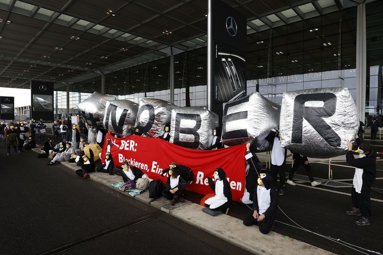 Aktivis lingkungan hidup mengenakan pakaian penguin dan membentangkan spanduk raksasa bertuliskan No BER di depan terminal utama bandara Berlin Brandenburg Willy Brandt, dalam unjuk rasa pembukaan bandara tersebut pada Sabtu (31/10/2020).