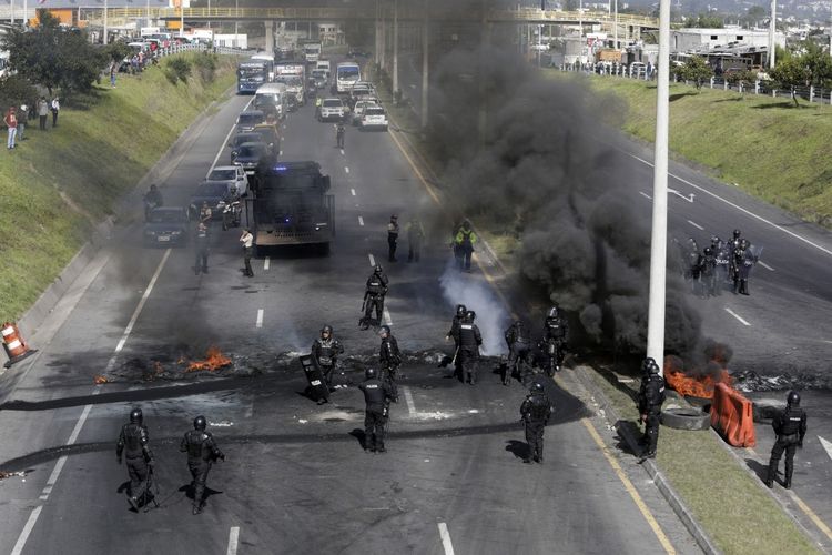 Polisi antihuru-hara membersihkan sebagian blokade jalan di jalan raya Ruta Viva, yang mengarah ke bandara Mariscal Sucre, dalam rangka protes yang dipimpin masyarakat adat terhadap harga bahan bakar dan biaya hidup yang tinggi, di Quito pada 17 Juni 2022.