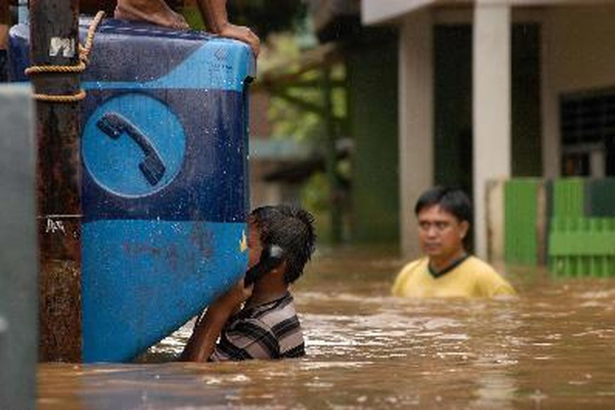 Seorang anak tengah bermain telepon umum yang ikut terendam di Kampung Pulo, Kampung Melayu, Jakarta Timur, Rabu (2/1). Akibat hujan turun sejak semalam,  air sungai Ciliwung meluap dan merendam dua RW di Kampung Melayu sejak pukul 02.30 wib.    Kristianto Purnomo  2/1/2008