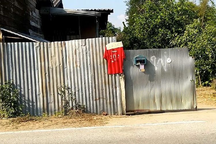 Warga Desa Ban Pak Huai Mai Ngamdi di Kota Mueang, Provinsi Tak, Thailand, menggantungkan baju berwarna merah di depan rumahnya sebagai upaya untuk menangkal serangan hantu janda yang dipercaya menjadi penyebab kematian pria di sana. Waktu pengambilan foto tidak disebutkan secara pasti.