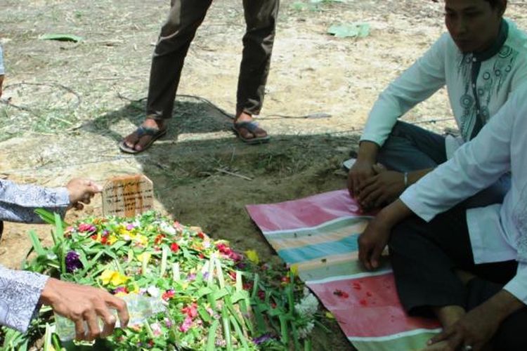 Adlin Nasution di atas kuburan anaknya Anggi yang meninggal usai dioperasi yang ketiga kalinya, Senin (27/7/2017)