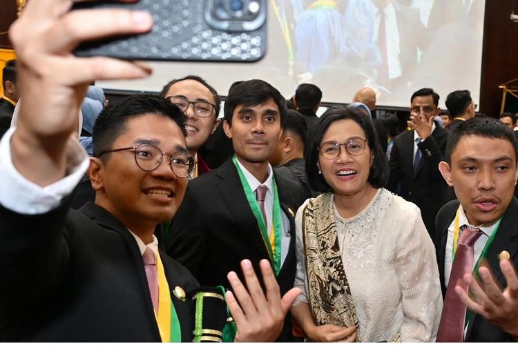 Sri Mulyani tampil elegan di wisuda putranya. Kenakan tunik putih tulang, batik cokelat, hingga heels nude, ini detail gaya anggunnya.