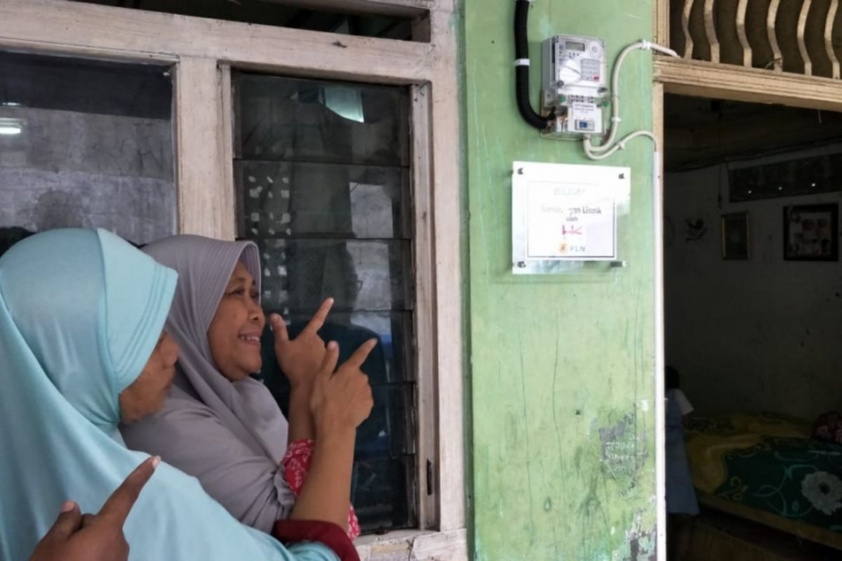 Eni Nurbayeni (kerudung abu-abu), warga Kota Bekasi yang rumahmya disambungkan listrik gratis dari PLN saat tunjukan meteran listrik di rumahnya, Jumat (25/1/2019).