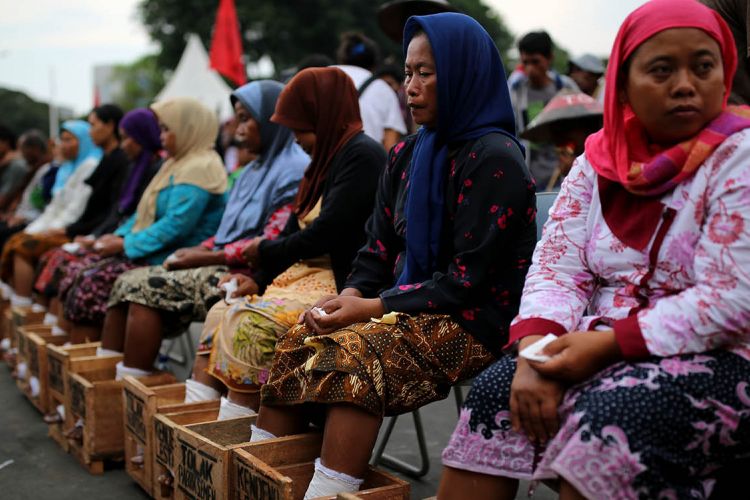 Patmi berkerudung biru (48 tahun) salah seorang petani perempuan asal kawasan Pegunungan Kendeng yang melakukan aksi mengecor kaki di depan Istana Negara, Jakarta, meninggal dunia pada Selasa (21/3/2017) dini hari. Patmi mengalami serangan jantung dan meninggal dalam perjalanan dari kantor LBH Jakarta menuju Rumah Sakit St. Carolus, Salemba, Jakarta Pusat.