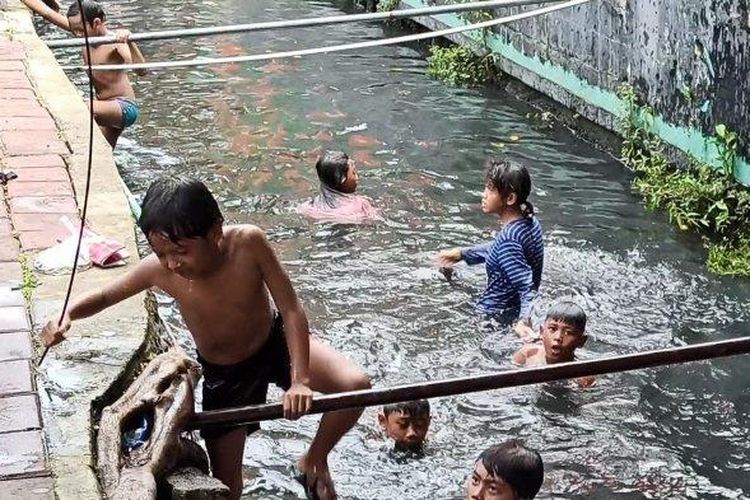 Selokan di Jalan Mangga Dua Raya, tepatnya depan kawasan Ruko Grand Boutique Mangga Dua, Pademangan, Jakarta Utara, menjadi tempat anak-anak bermain dan berenang, Kamis (4/4/2021). 