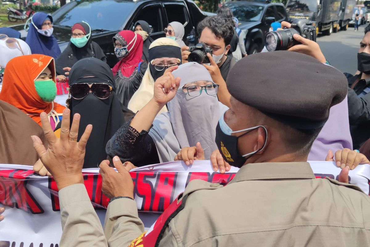 Polisi melarang massa Rizieq Shihab untuk berorasi dan membentangkan spanduk di Pengadilan Negeri Jakarta Timur, Jumat (19/3/2021). Massa ibu-ibu yang berjumlah sekitar 20 orang itu pun akhirnya diusir mundur sampai ke belakang gedung pengadilan. 