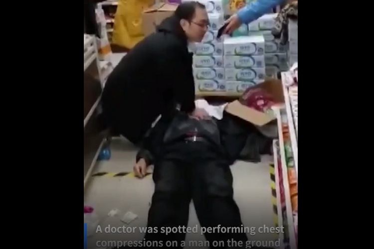 Seorang dokter menolong pria lansia yang tiba-tiba pingsan terjatuh di tengah maraknya penyebaran virus corona. (Xinhua)