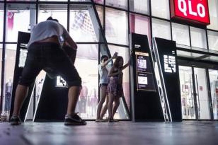 Terlihat warga mengambil foto selfie di luar gerai Uniqlo di Beijing sambil menirukan gaya bercinta pasangan yang ditahan aparat Tiongkok