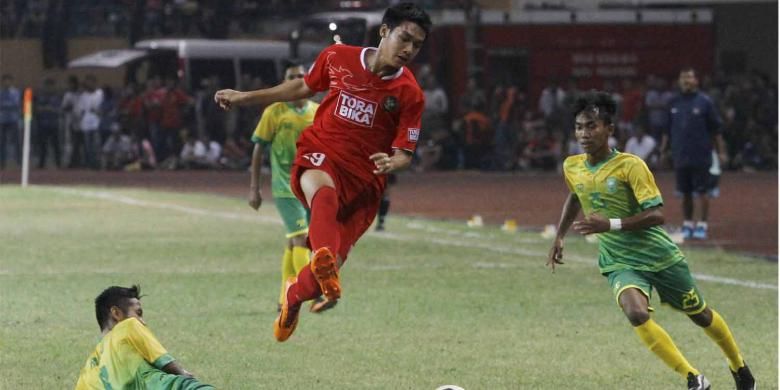Striker Timnas U-19 Septian David Maulana melompat menghindari hadangan pemain tim Pra-Pon Riau Novrianto pada laga Tur Nusantara Timnas U-19, Senin (16/6/2014) di Stadion Utama Riau, Pekanbaru. Timnas U-19 berhasil melibas tuan rumah Riau dengan skor 4-0.  