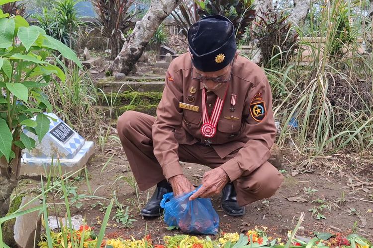 Amad menaburkan bunga di makam Supiah