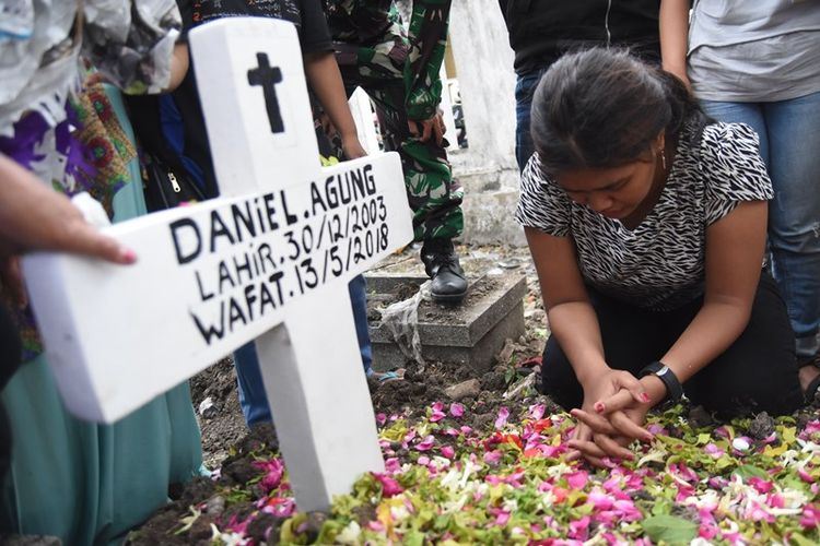 Novi (kanan) kakak dari Daniel Agung Putra Kusuma korban bom bunuh diri di Gereja Pantekosta Pusat Surabaya (GPPS) berada disamping pusara ketika pemakaman di Makam Putat Gede Surabaya, Jawa Timur, Selasa (15/5). Daniel merupakan korban mobil bom bunuh diri di Gereja Pantekosta Pusat Surabaya (GPPS) Arjuna, Surabaya Minggu (13/5) lalu. 