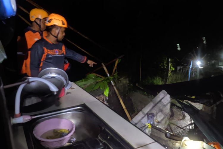 TANAH LONGSOR: Satu orang dilaporkan tewas setelah tanah longsor menimpa rumah warga di Desa Tileng, Kecamatan Dagangan Kabupaten Madiun, Jawa Timur, Sabtu (21/12/2024) petang. Petugas BPBD Madiun menunjukkan lokasi korban tersengat listrik saat hendak menyelamatkan barang usai rumah runtuh diterjang tanah longsor. 