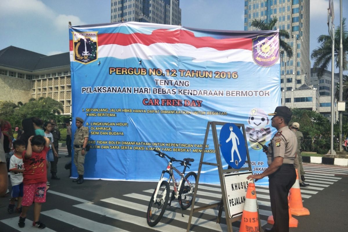 Satpol PP DKI Jakarta memasang banner berisikan larangan pelaksanaan kegiatan partai digelar di kawasan Car Free Day (CFD) atau hari bebas kendaraan bermotor (HBKB), Minggu (6/5/2018).