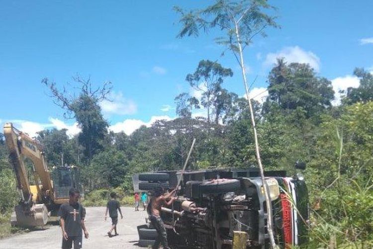 Warga sedang bahu membahu melakukan evakuasi dump truck yang terbalik di Jalan Trans Nabire Kabupaten Mimika, Selasa (22/11/2022). (Tribun Papua/Marselinus Labu Lela)