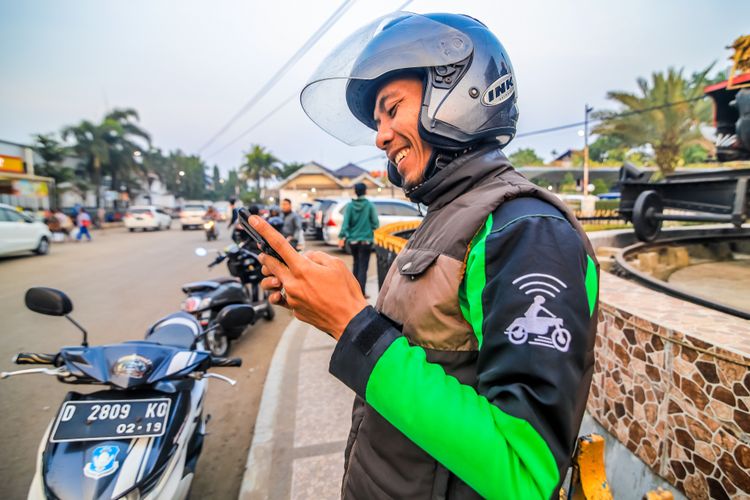 Ilustrasi driver Gojek sedang memegang handphone, menunggu order dari customer. 