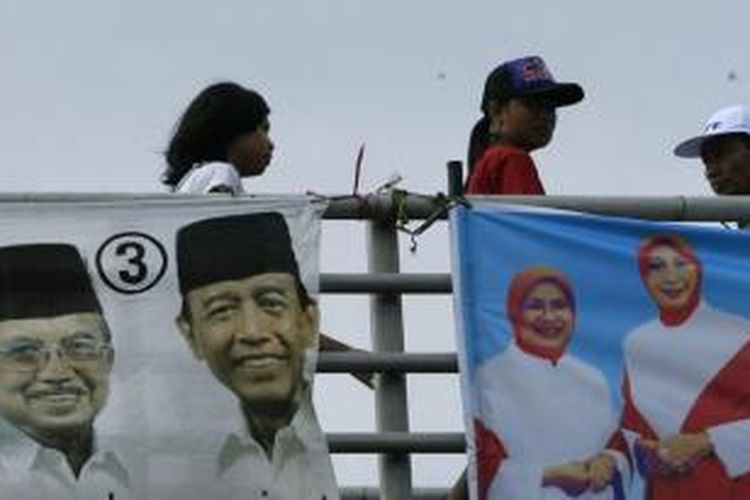 Ilustrasi baliho kampanye: Warga melintas di samping spanduk calon presiden - calon wakil presiden Jusuf Kalla - Wiranto beserta istrinya di jembatan penyeberangan orang Jalan Otista, Jakarta Timur, Selasa (2/6/2009).   