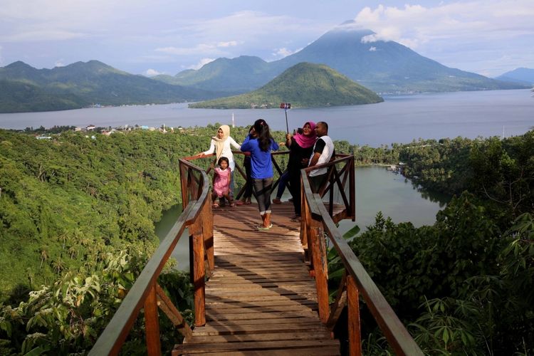 Wisatawan sedang menikmati pemandangan Pulau Maitara, Pulau Tidore, dan Danau Laguna di Desa Fitu, Ternate, Maluku Utara, Minggu 28/05/2017. Pemandangan di bagian belakang uang seribu rupiah menampilkan lukisan Pulau Tidore, Pulau Maitara dan aktivitas nelayan menjala ikan menjadi penambah sisi humanis di lukisan uang seribu rupiah tersebut.