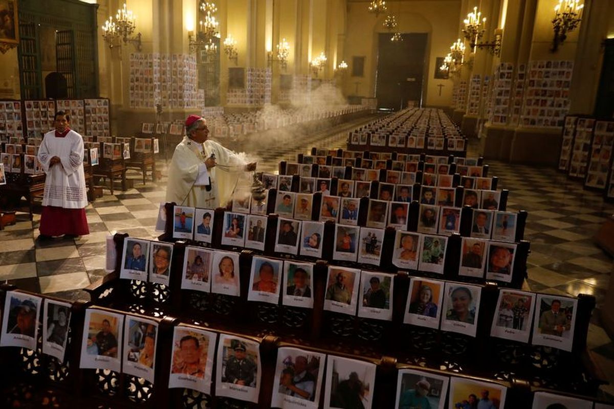 Uskup Agung Lima, Carlos Castillo, ketika memberkati foto korban meninggal Covid-19 saat memimpin misa Minggu di katedral Peru (14/6/2020).