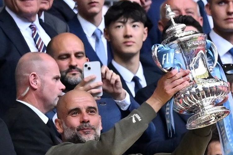 Pelatih Manchester City asal Spanyol, Pep Guardiola, saat memegang trofi Piala FA 2022-2023 usai menang atas Man United di Stadion Wembley pada 3 Juni 2023. (Foto oleh Glyn KIRK / AFP).