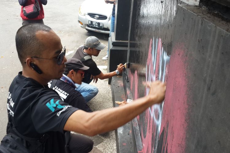 Sejumlah warga yang tergabung dalam Malang Musik Bersatu saat menghilangkan bekas vandalisme oleh sekolompok massa berpakaian hitam di Jembatan Majapahit, Kota Malang, Kamis (2/5/2019)