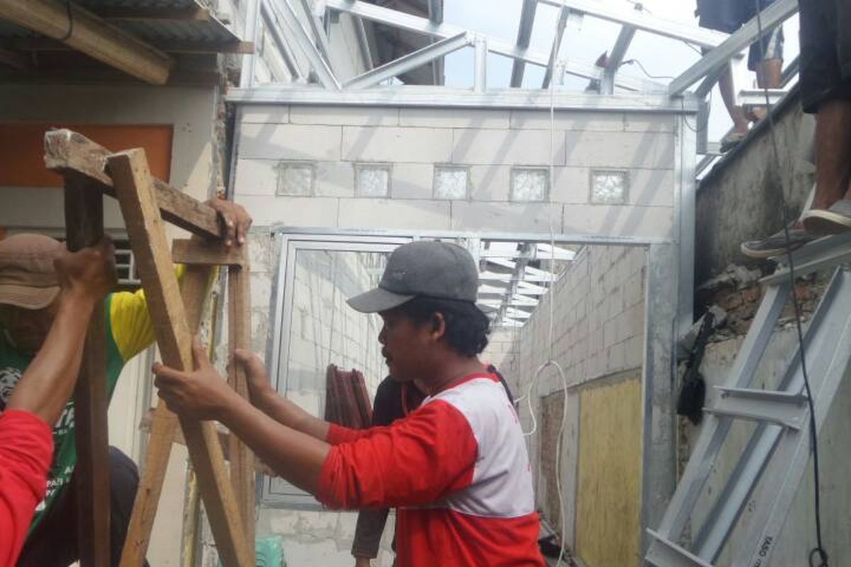 Pasukan merah dan petugas PPSU sedang melakukan pemasangan atap dan tembok di rumah-rumah yang termasuk dalam program bedah rumah yang dicanangkan Pemprov DKI Jakarta, Jumat (5/5/2017).