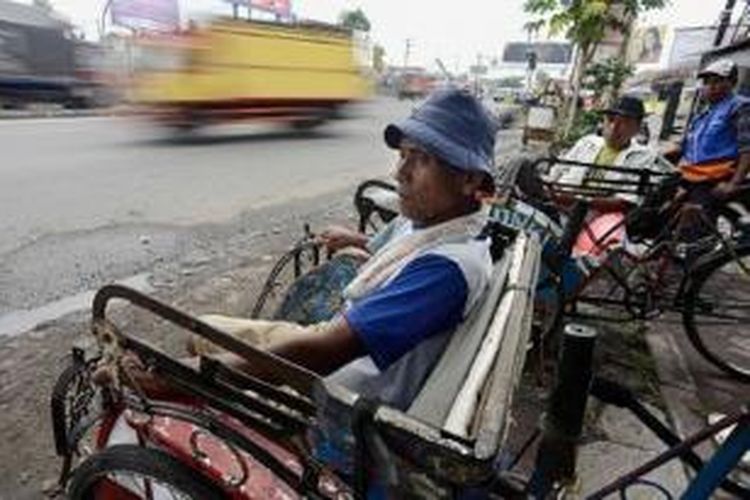 Suara (53, kiri) dan Suta (40, kedua dari kiri) menanti penumpang becak di Simpang Palimanan, Cirebon, Jawa Barat, Senin (22/7). Setiap hari mereka memperoleh penghasilan sekitar Rp 20.000. Semakin banyaknya becak bermesin serta ojek sepeda motor yang beroperasi membuat jumlah penumpang becak kian berkurang.