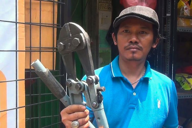 Kastijo (41), salah satu pegawai yang berhasil menggagalkan pencurian di tokonya, memegang sebuah gunting yang digunakan para pencuri saat beraksi, Lubang Buaya, Cipayung, Jakarta Timur, Kamis (31/8/2023).