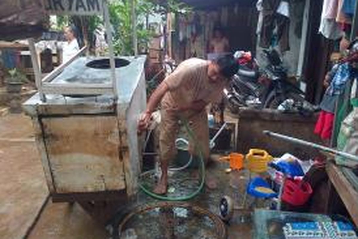 Salah seorang warga RW 05 Kedoya Selatan, Jakarta Barat sedang membersihkan gerobak dagangannya akibat terendam banjir, Jumat (13/2/2015)