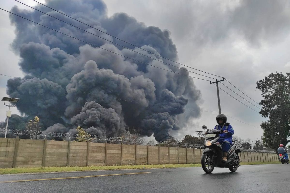 Seorang pengendara motor tampak sedang melintas di lokasi terbakarnya tangki minyak di Kilang Balongan. Akibat kebakaran ini  PT Pertamina (Persero) kehilangan 92.000 kl (kiloliter) minyak dari 4 tangki yang terbakar. 