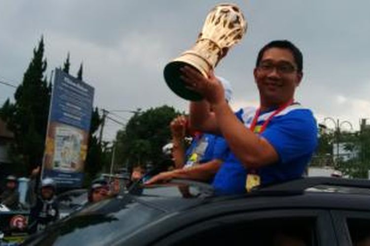 Wali Kota Bandung Ridwan Kamil memegang piala kemenangan Persib saat melakukan arak - arakan dengan ribuan bobotoh mengelilingi Kota Bandung, Sabtu, (8/11/2014).