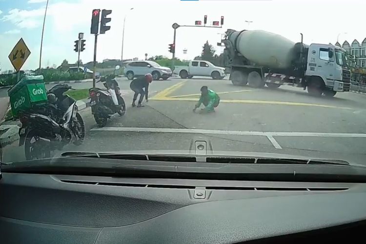 Tangkapan layar dari video viral driver ojol dan pengendara motor berhenti untuk memunguti paku yang berserakan di tengah jalan. Peristiwa ini diyakini terjadi di Melaka, Malaysia.
