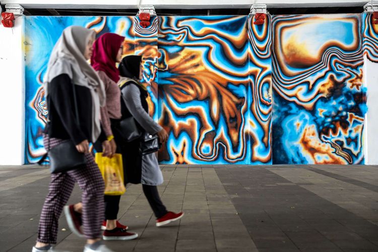 Warga melintasi mural karya dari seniman asal Berlin, Jerman Snyder di terowongan Jalan Kendal, Jakarta Pusat, Senin (29/7/2019). Tema Mural yaitu Persahabatan untuk perayaan 25 tahun hubungan antara Jakarta dan Berlin sebagai Sister City.