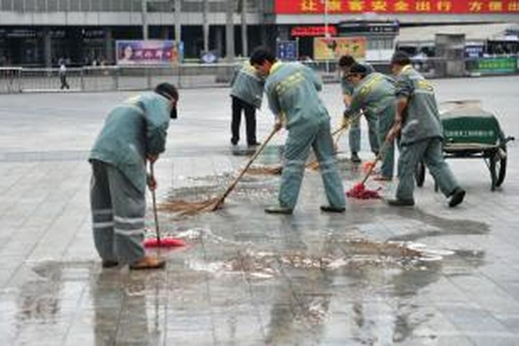 Para pekerja membersihkan noda darah di pelataran stasiun KA Guangzhou, China akibat insiden penusukan yang melukai enam orang calon penumpang pada Selasa (6/5/2014).