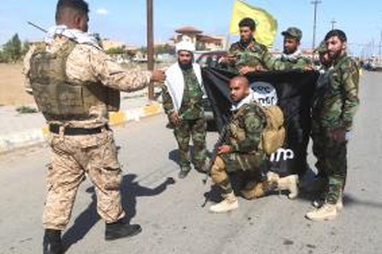 Sejumlah personel militer Irak dan milisi Syiah berfoto bersama usai merebut kota Al-Alam yang terletak di sebelah utara kota Tikrit dari tangan ISIS.