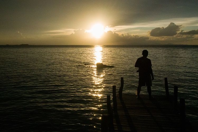 Seorang wisatawan tengah menikmati pemandangan matahari terbenam dan hamparan laut lepas di area dermaga tepi pantai di Kasuari Valley Beach Resort di Kota Sorong, Papua Barat, Senin (25/10/2021).