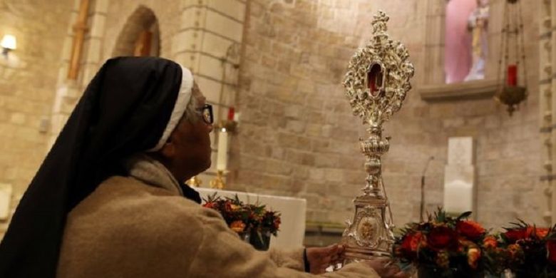 Seorang biarawati memperhatikan tongkat berisi potongan kayu yang diyakini berasal dari palungan Yesus. Setelah berada di Eropa lebih dari 1.000 tahun, potongan kayu tersebut bakal dikembalikan ke Betlehem.