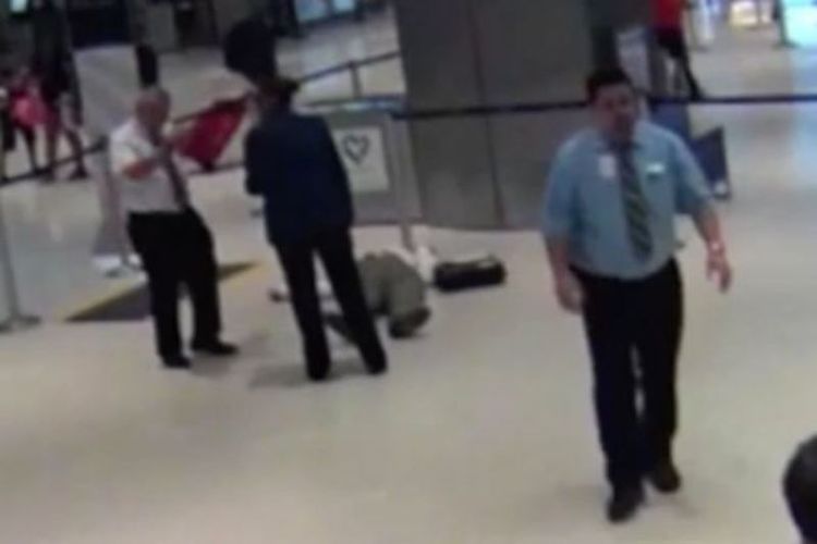 Dalam foto yang diambil dari rekaman CCTV ini terlihat Ronald Tiger (71) tergeletak di lantai bandara internasional George Bush, Texas, AS setelah didorong seorang star United Airlines Alejandro Anastasia (baju biru) yang melenggang santai usai insiden tersebut.