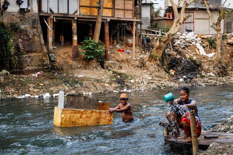 Warga beraktivitas di pemukiman padat penduduk di bantaran Sungai Ciliwung, Manggarai, Jakarta, Minggu (28/7/2019). BPS mencatat tingkat kemiskinan di Indonesia turun pada Maret 2023.