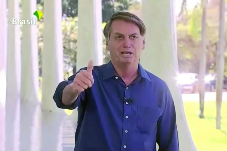 Presiden Brasil Jair Bolsonaro mengacungkan jempol ke hadapan wartawan, saat ditemui usai dinyatakan positif Covid-19 pada Selasa (7/7/2020).