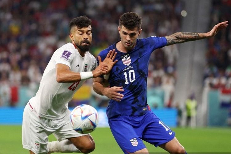 Hasil Iran vs Amerika Serikat: Christian Pulisic (kanan) berduel dengan Ramin Rezaeian (kiri) pada laga Grup B Piala Dunia 2022 Qatar yang mempertemukan Iran vs Amerika Serikat di Al Thumama Stadium, Doha, Rabu (30/11/2022) dini hari WIB. Gol tunggal Pulisic mengantar timnas Amerika Serikat mengalahkan Iran 1-0 dan lolos ke babak 16 besar Piala Dunia 2022 Qatar. Terkini, Pulisic dikabarkan siap bergabung dengan AC Milan.