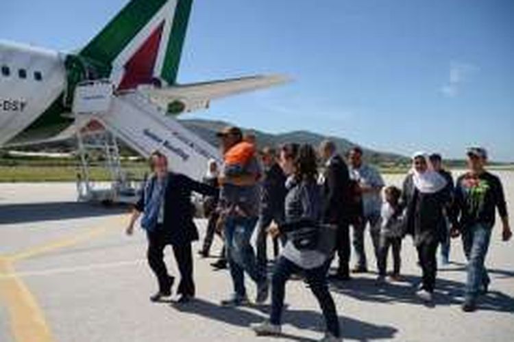 Dalam foto ini terlihat sejumlah pengungsi Suriah berjalan di landas pacu bandara Pulau Lesbos, Yunani menuju pesawat terbang yang membawa Paus Fransiskus. Pemmimpin gereja Katolik itu memboyong tiga keluarga pengungsi ke Italia.